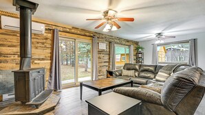 A cozy living room with a fireplace, leather sofa, and a ceiling fan. - Canal-front Cabin: Dock & Fire Pit in New Lisbon (New Lisbon)