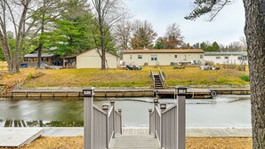 A wooden staircase leading to a dock over a calm body of water, surrounded by trees and a row of houses. - Canal-front Cabin: Dock & Fire Pit in New Lisbon (New Lisbon)