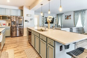A modern kitchen with a large island, stainless steel appliances, and a seating area with a sofa and dining table. - 15 Mi to Dtwn Indianapolis: Family-friendly Home! (Brownsburg)
