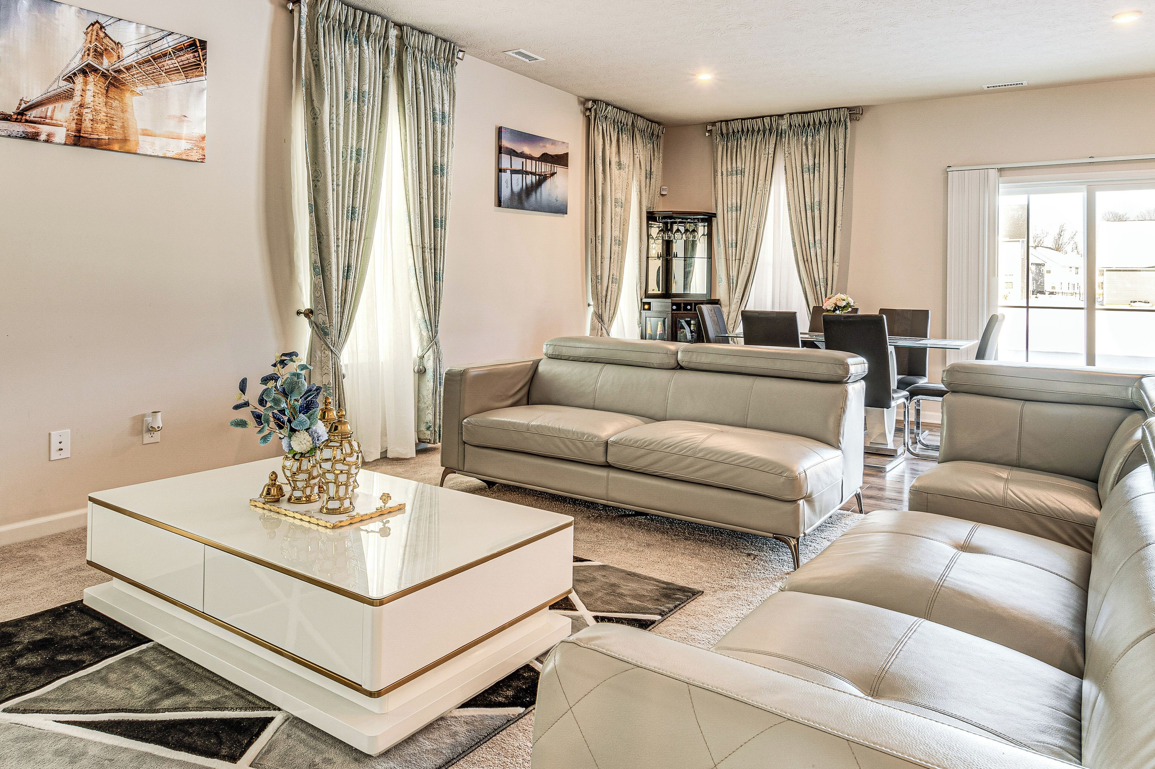 A modern living room with a beige sofa, a white coffee table, and a dining area with a glass-top table.