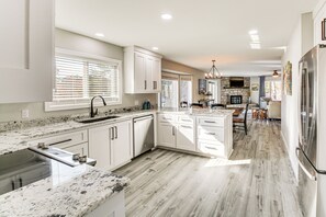 A modern kitchen with white cabinets, granite countertops, and a large island. - Waterfront Lake Coronado Home w/ Deck & Views (Hot Springs Village)
