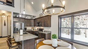 A modern kitchen with granite countertops, stainless steel appliances, and a large island with bar stools. - Hot Tub & Trail Access: Black Hills, Rally Stay! (Lead)