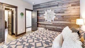 A bedroom with a geometric patterned rug, a star-shaped wall decoration, and a bed with patterned bedding. - Hot Tub & Trail Access: Black Hills, Rally Stay! (Lead)