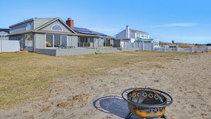 A modern house with a large patio area, a fire pit, and a view of the beach. - Bayfront Home in Patchogue w/ Deck & Fishing Dock (Patchogue)