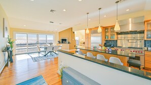 A modern kitchen with a large island, stainless steel appliances, and a dining area with a view. - Bayfront Home in Patchogue w/ Deck & Fishing Dock (Patchogue)