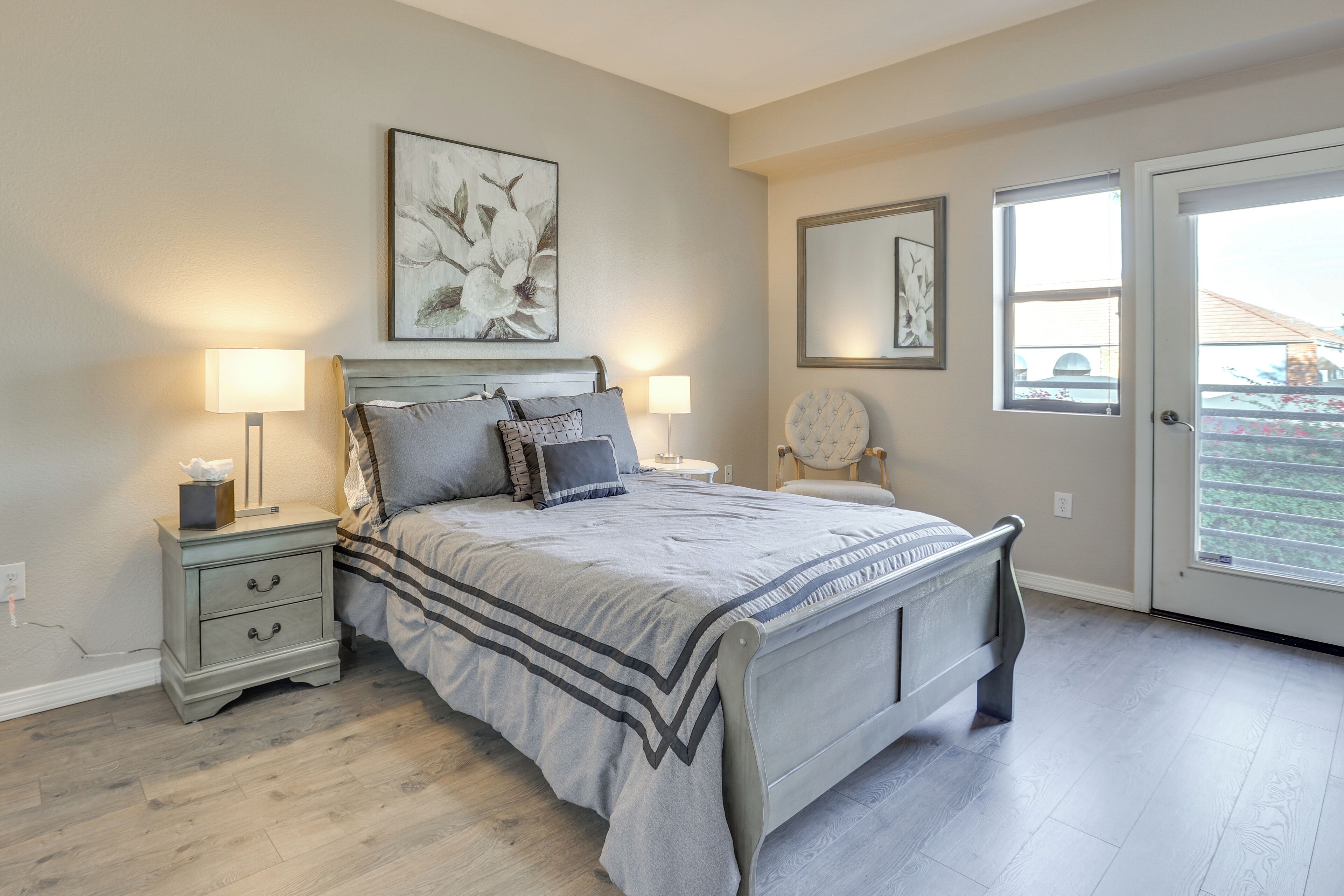 A bedroom with a bed, nightstands, a dresser, and a large window.