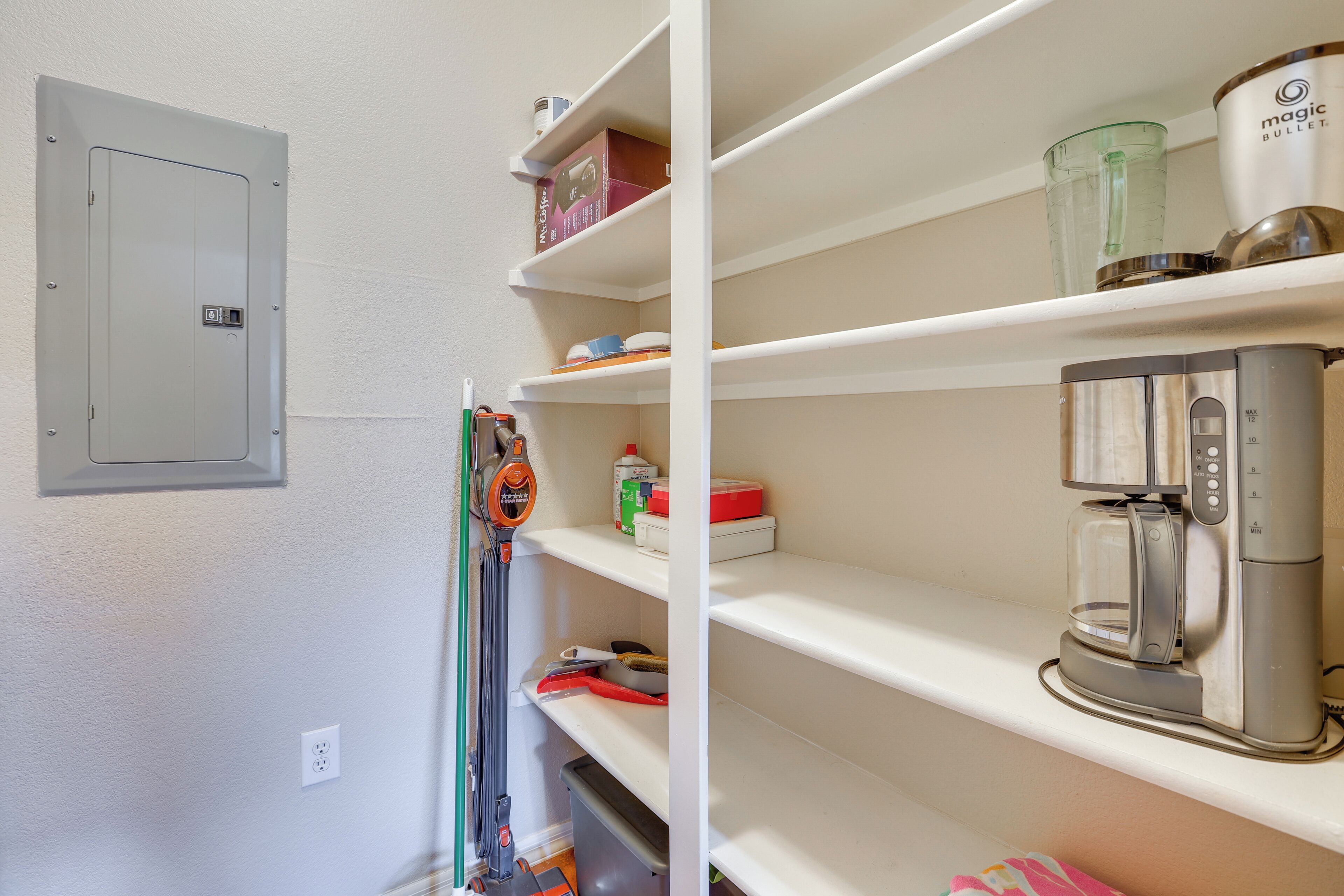 A kitchen with white shelves, a coffee maker, and a microwave.