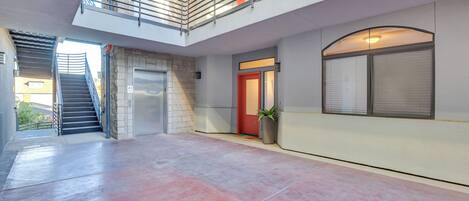 A spacious indoor area with a red door, a staircase, and a large window.