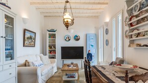 Uma sala de estar com sofá, mesa de centro, TV e pratos decorativos.