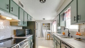 Una cucina con mobili verdi, un forno a microonde, un fornello e un lavello.
