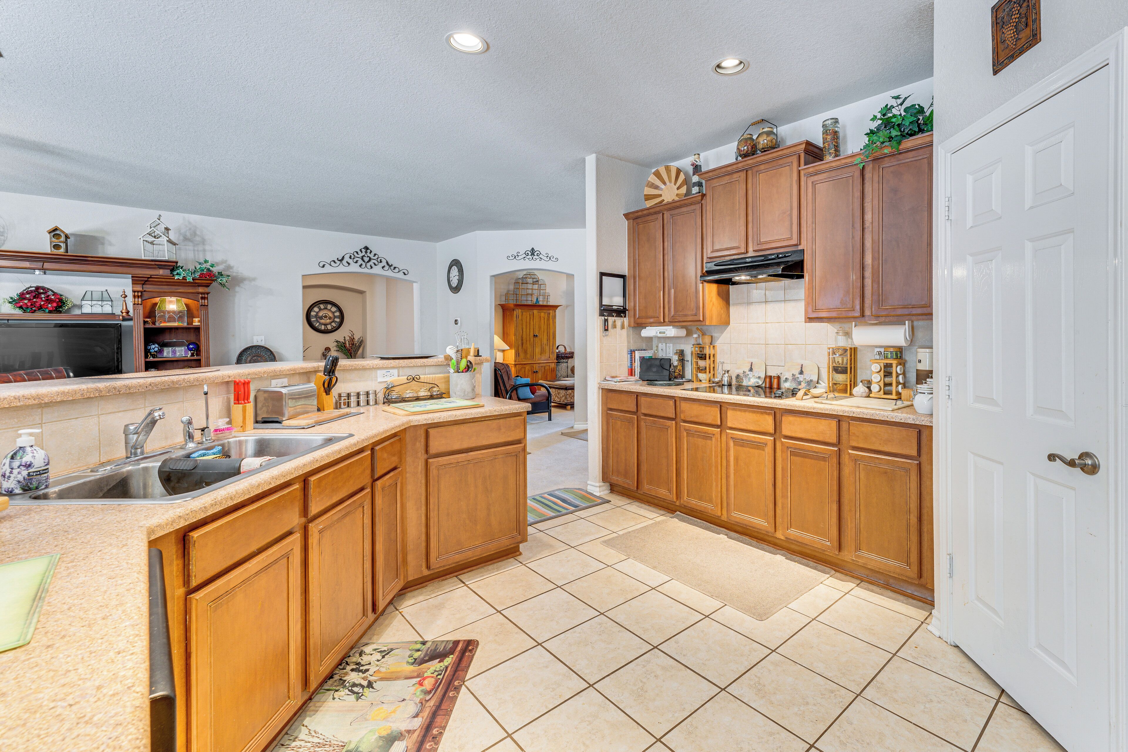 A spacious kitchen with wooden cabinets, a large island, and a white door.