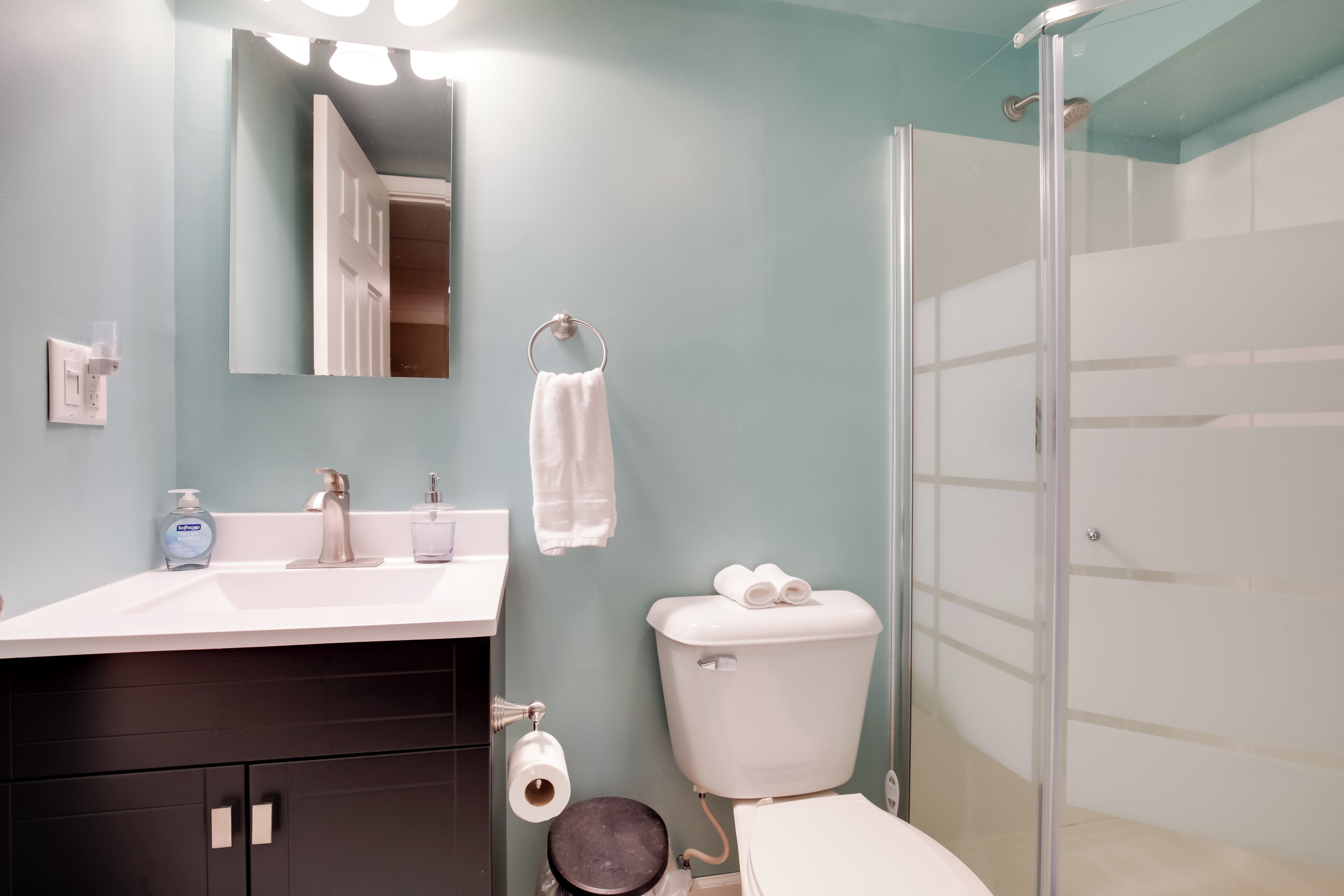 A bathroom with a sink, mirror, toilet, and shower.