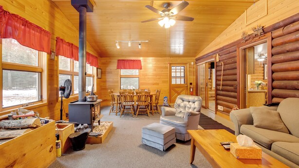 L’intérieur d’une cabane en rondins, avec une cheminée, des meubles en bois et un ventilateur de plafond.