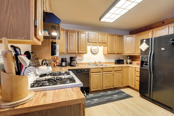 A modern kitchen with wooden cabinets, a gas stove, a dishwasher, a refrigerator, and a microwave. - Family Gem Near the Chain of Lakes in Eagle River! (Eagle River)