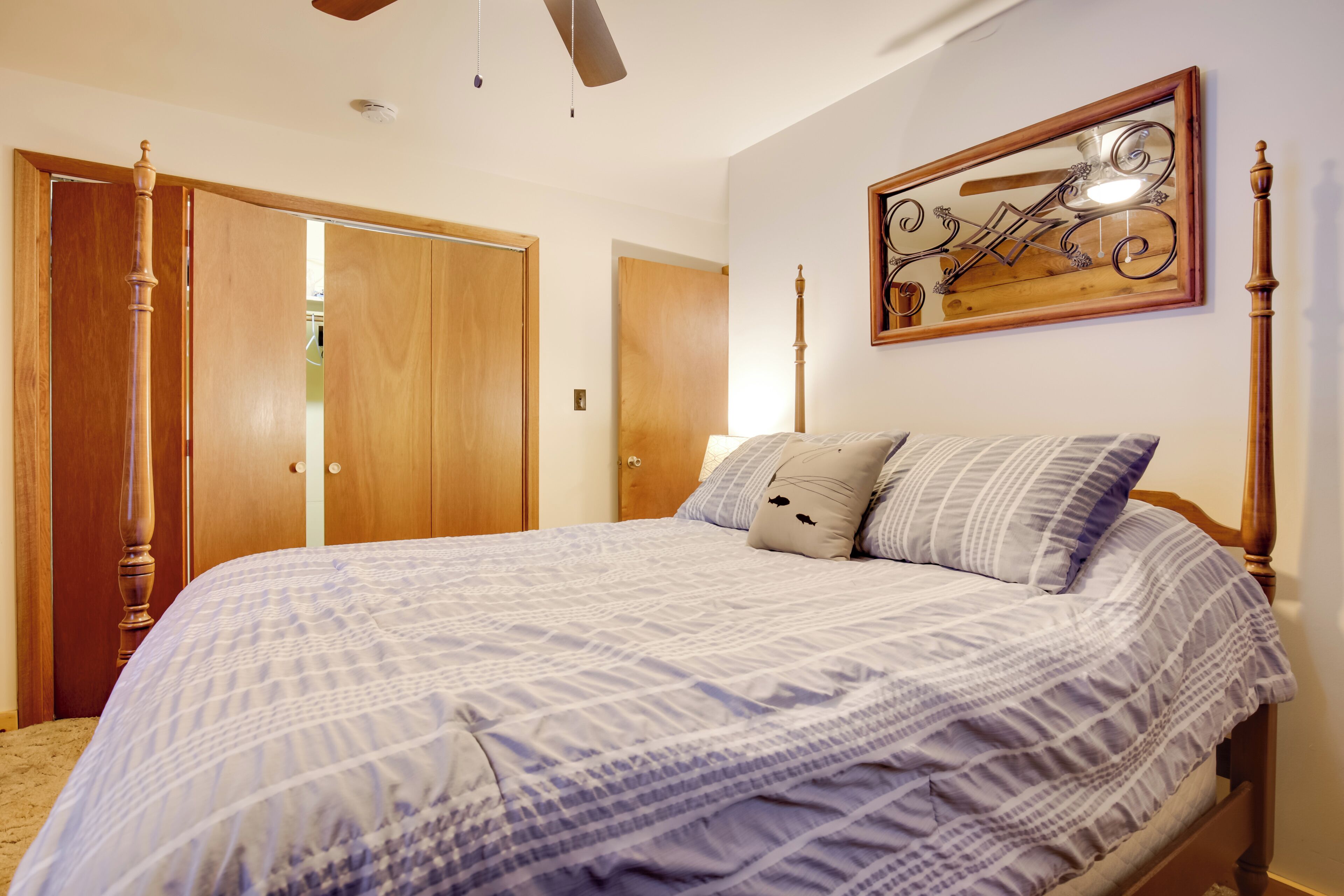 A bedroom with a large bed, wooden wardrobe, and a ceiling fan.