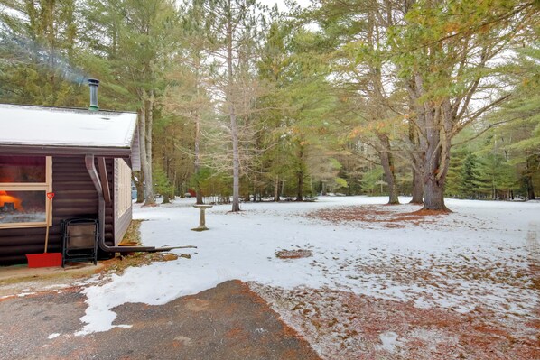 A cabin with a chimney, surrounded by trees and snow.