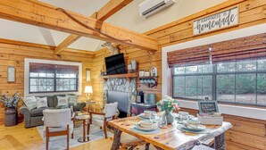 Interior acogedor de una cabaña con una mesa de comedor de madera dispuesta para cuatro personas, un sofá y una chimenea.