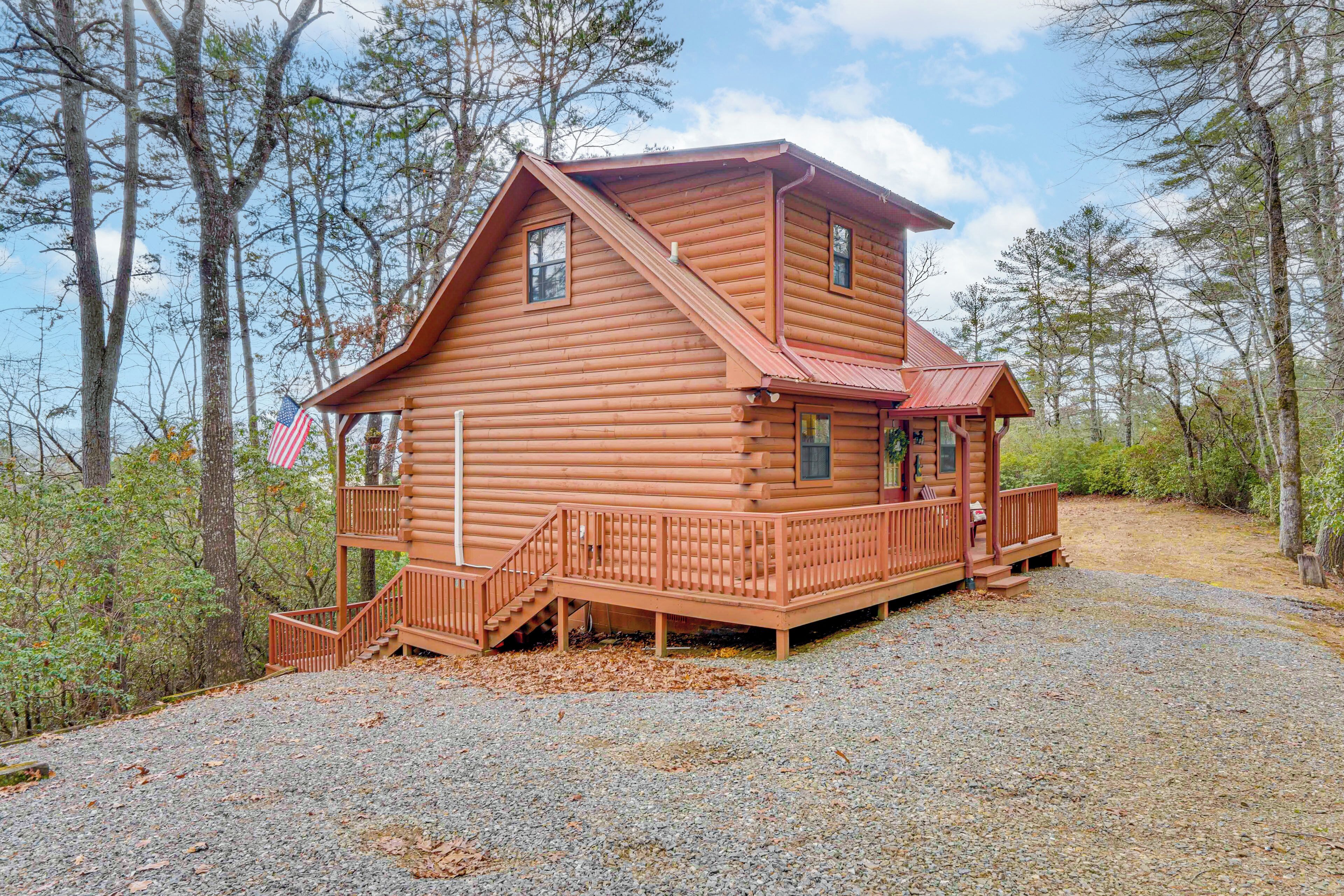 A log cabin with a porch, a staircase, and an American flag.