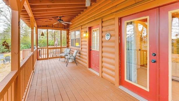 Una terraza de madera con una puerta roja, un ventilador de techo y mobiliario exterior.