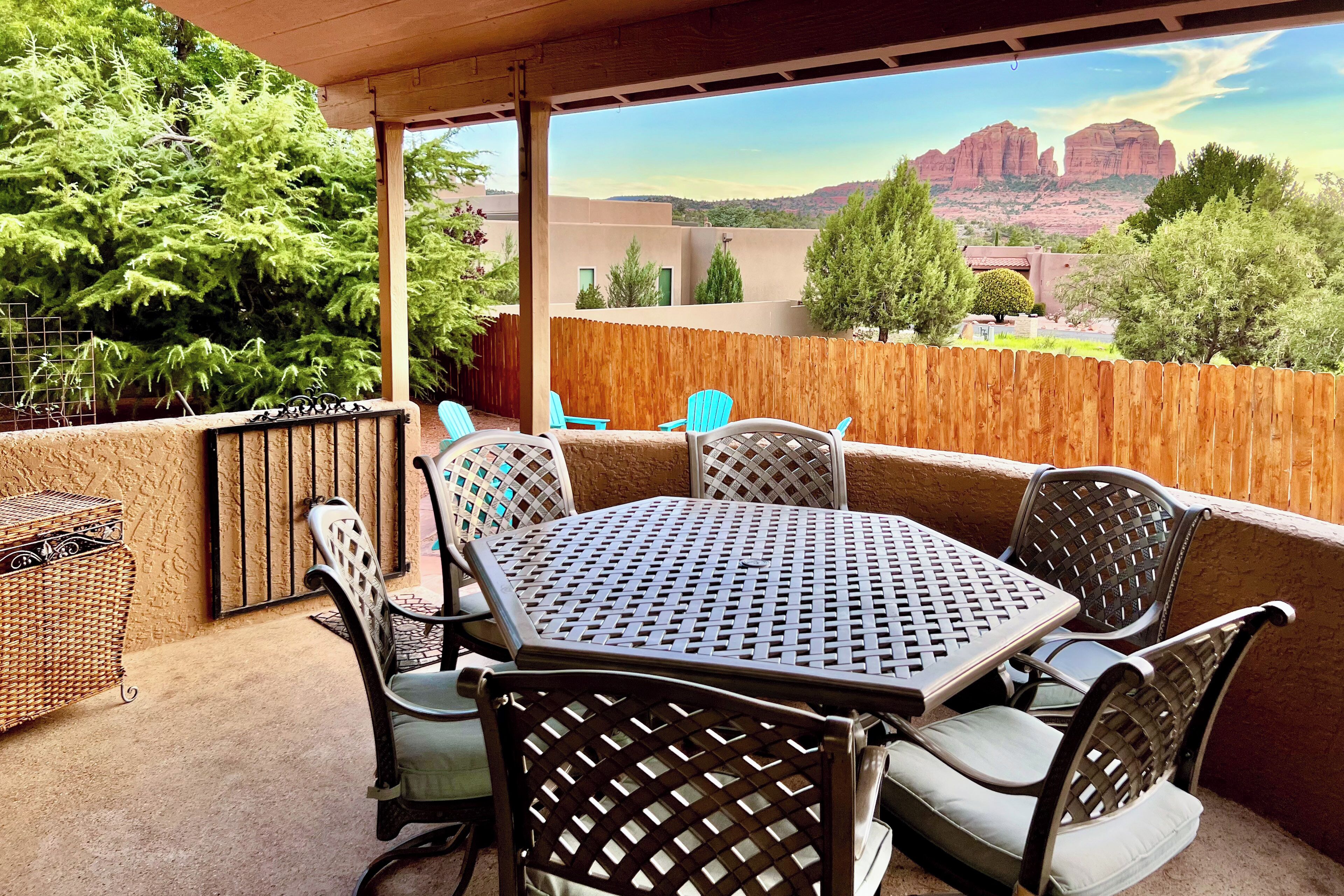 Un patio con una mesa y sillas, una cesta de mimbre y vistas a formaciones rocosas rojizas.