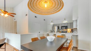 Une cuisine moderne avec des meubles blancs, un four à micro-ondes et une cuisinière. On y trouve également un coin repas avec une grande table et des chaises.