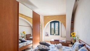 A bedroom with a bed, a mirror, a window, and a wooden wardrobe.