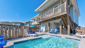 A pool area with a wooden deck, lounge chairs, and a covered seating area. - Save The Ales~Boardwalk~Private Pool~Sleeps 10! (Port Aransas)