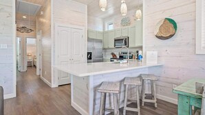 A spacious kitchen with a large island, wooden cabinets, and pendant lighting. - Save The Ales~Boardwalk~Private Pool~Sleeps 10! (Port Aransas)