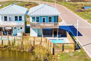 Two beachfront houses with balconies, a wooden deck, and a swimming pool.