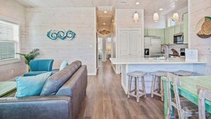A modern kitchen with white cabinets, a central island with stools, and pendant lighting. - Save The Ales~Boardwalk~Private Pool~Sleeps 10! (Port Aransas)