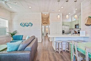 Une cuisine moderne avec des meubles blancs, un îlot central doté de tabourets et un éclairage suspendu.