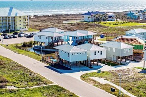 A coastal residential area with multiple houses, a parking lot, and a large building in the background.