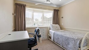 A bedroom with a bed, a desk, a chair, a window with curtains, and a ceiling fan. - Hidden Gem (Hamilton)