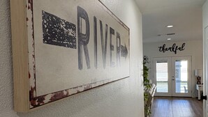 Un passadís amb un senyal de 'RIVER', una decoració mural amb la paraula 'thankful' i un paviment de fusta.
