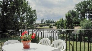 Ein runder weißer Tisch mit vier Stühlen und einem Blumentopf mit roten Blüten.