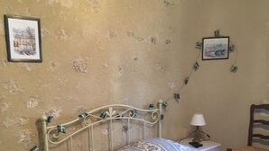 Ein Schlafzimmer mit einem Bett, einem Nachttisch, einem Sessel und einer Wand mit Bildern.