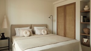 A bedroom with a bed, bedside table, lamp, and a wardrobe.