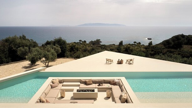A poolside area with a seating arrangement and a view of the sea.
