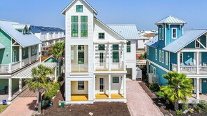 A multi-story coastal house with a balcony, a small porch, and a garden area. - Beautifully Constructed Beach Home In Cinnamon Shore North. (Port Aransas)