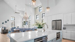 A spacious kitchen with a large island, stainless steel appliances, and a modern chandelier. - Beautifully Constructed Beach Home In Cinnamon Shore North. (Port Aransas)