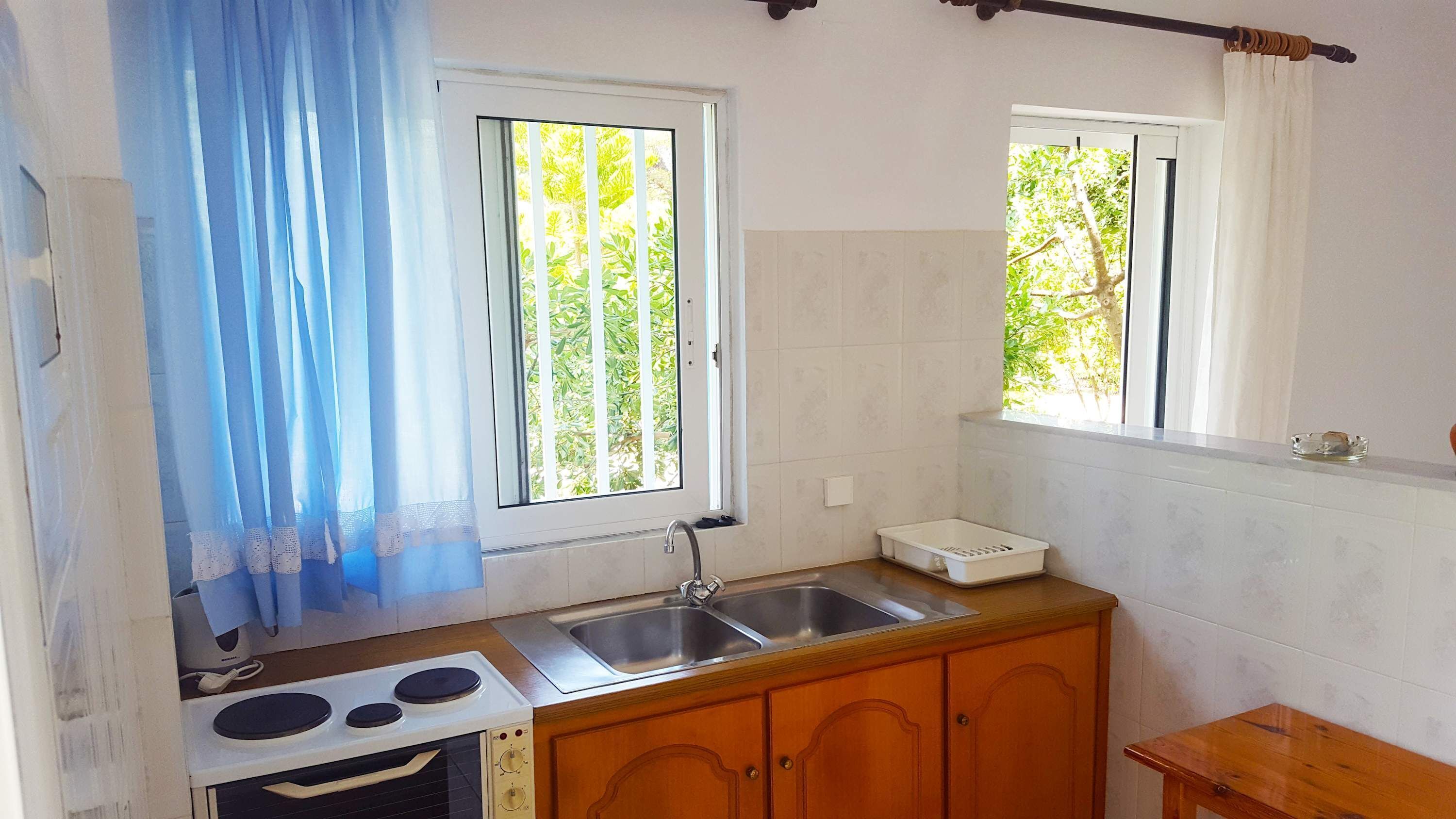 Une petite cuisine équipée d’une cuisinière, d’un évier et de meubles de rangement en bois.