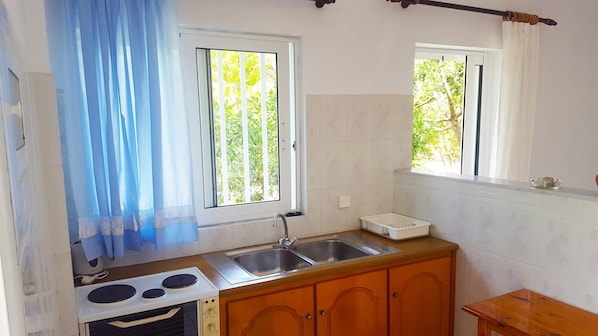 A small kitchen with a stove, sink, and wooden cabinets.