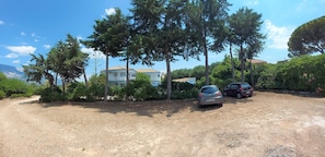 Un quartier résidentiel avec une maison, des voitures garées et des arbres environnants.