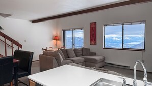 Una sala de estar moderna con sofá, mesa de comedor y área de cocina con pileta.