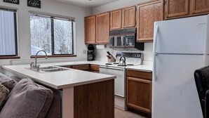 Una cocina con armarios de madera, un refrigerador blanco, una estufa y un lavaplatos.