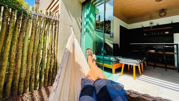 A hammock on a balcony with a view of a modern kitchen and dining area.