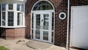 A corner building with a bay window, a white door with glass panels, and a brick facade. - 6-bed House - Sleeps 13 - Families & Contractors (Dudley)