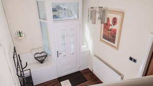 A white door with a glass panel, a heart-shaped decoration on the floor, a radiator, and a framed picture on the wall. - 6-bed House - Sleeps 13 - Families & Contractors (Dudley)