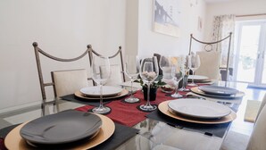 A dining table set with plates, glasses, and cutlery, with chairs around it. - 6-bed House - Sleeps 13 - Families & Contractors (Dudley)