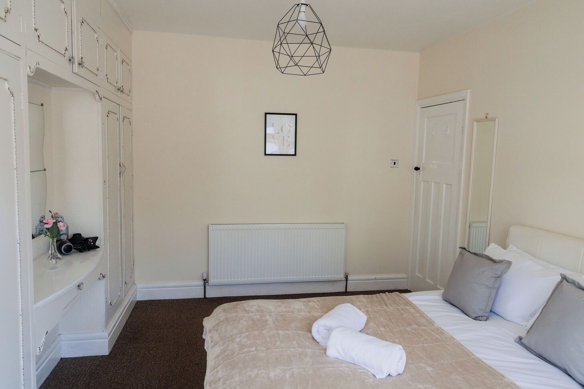 A bedroom with a bed, a radiator, a wardrobe, and a framed picture on the wall.